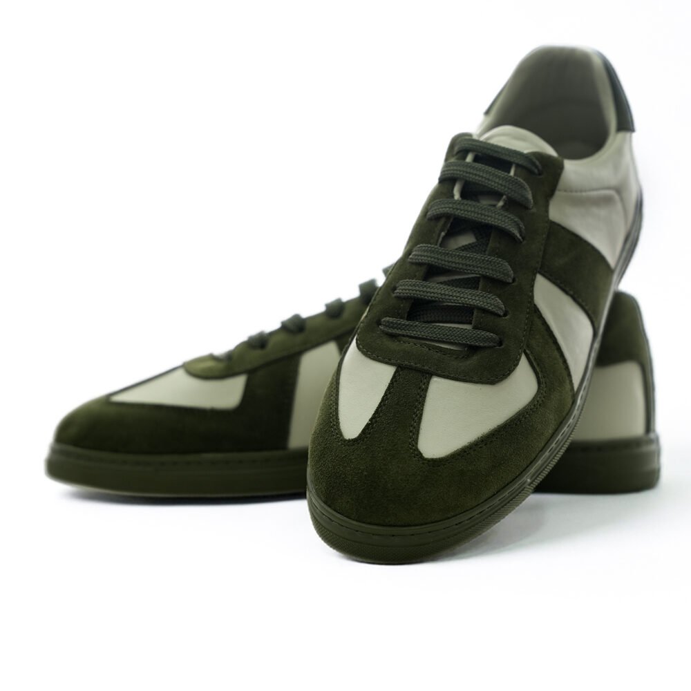 Haki süet ve krem deri kombinasyonlu low-top sneaker çiftinin önden ve açılı biçimde bir arada sunulduğu dinamik ürün çekimi