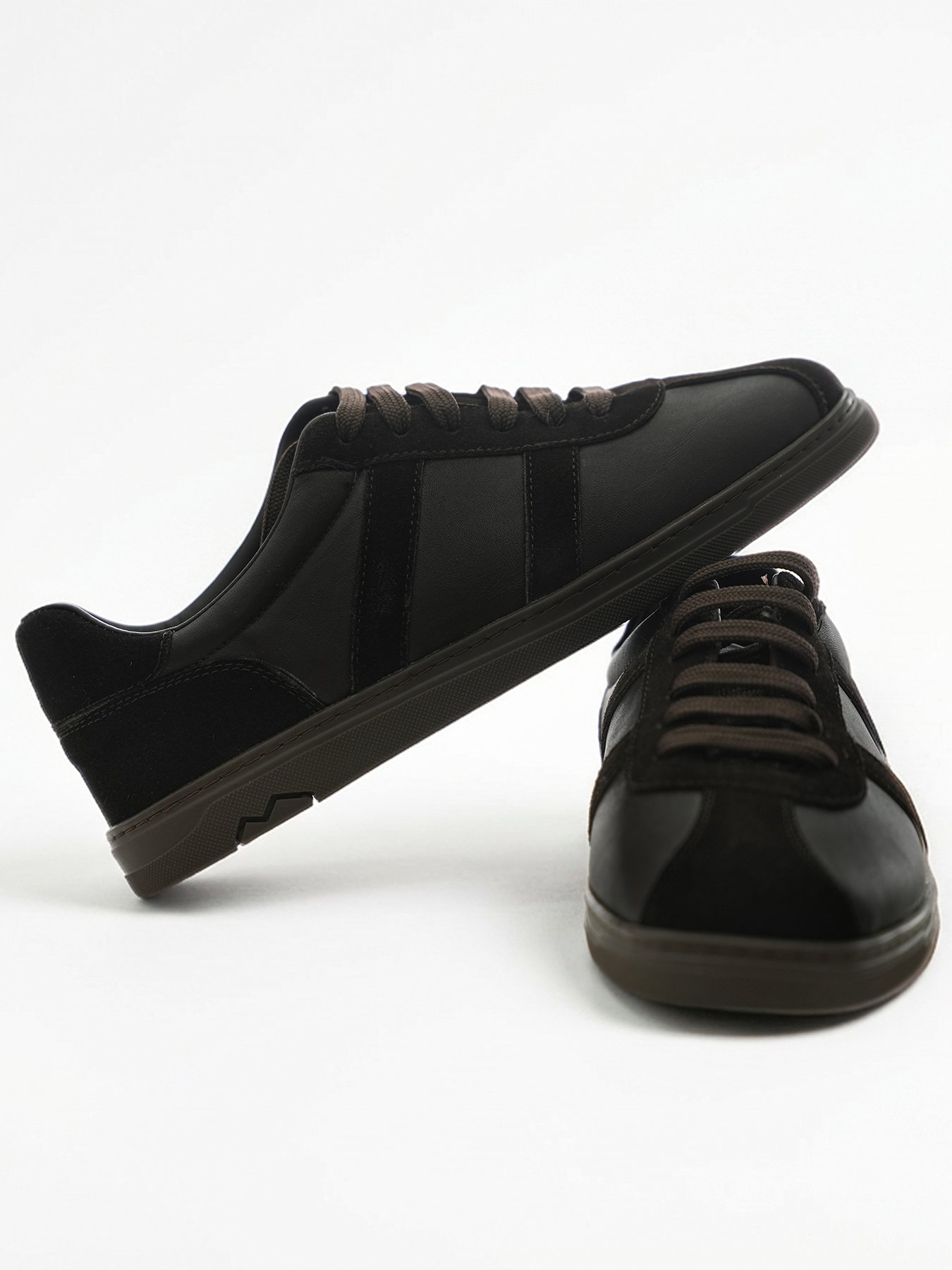 Kahverengi bağcıklı low-top erkek deri günlük sneaker çiftinin dinamik pozla sergilendiği ürün çekimi