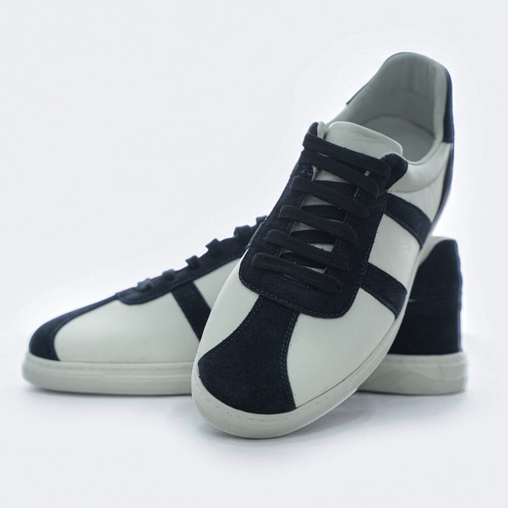 Beyaz deri ve lacivert süet panelli low-top erkek sneakerın farklı açılardan birlikte sunulan görüntüsü
