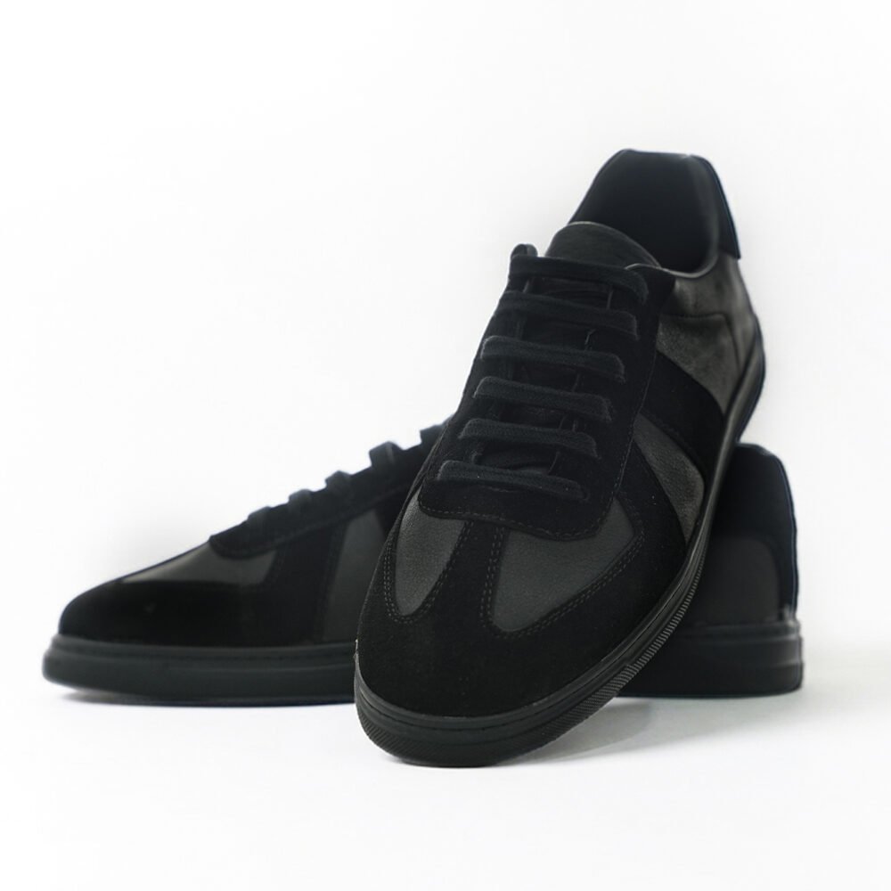 Siyah deri ve süet karışımı low-top sneaker çiftinin önden ve açılı pozda birlikte konumlandırıldığı dinamik ürün çekimi