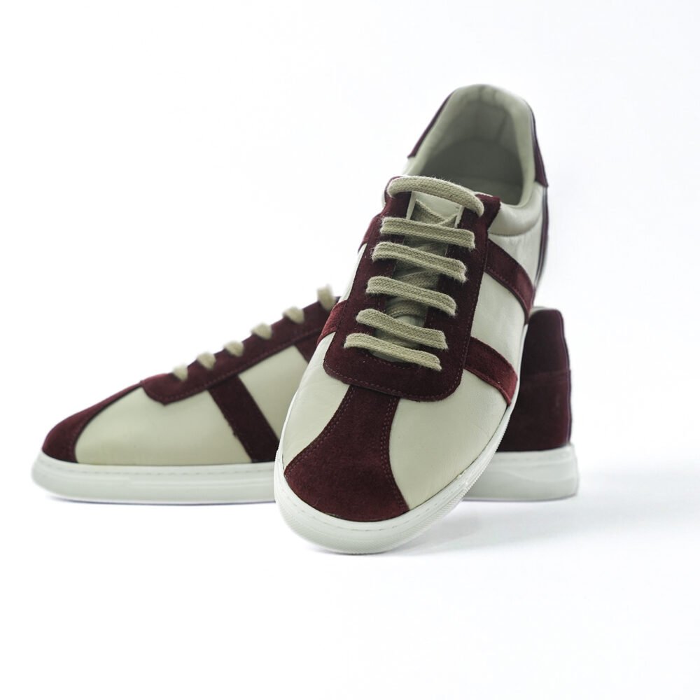 Bordo süet ve krem deri kombinasyonlu low-top erkek sneaker çiftinin önden ve açılı biçimde birlikte sunulduğu dinamik ürün fotoğrafı